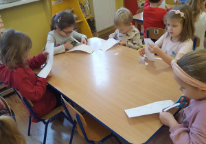 Dzieci wycinają koronę z papieru.
